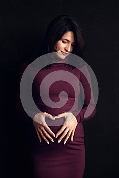 Pregnant happy Woman touching her belly. Pregnant middle aged mother portrait, caressing her belly and smiling close-up. Healthy P