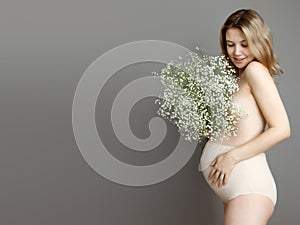 Pregnant happy Woman touching her belly. Pregnant young mother portrait, caressing her belly and smiling