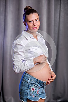 Pregnant happy woman touching her belly. Pregnant young mother portrait, caressing her belly and smiling. Healthy Pregnancy