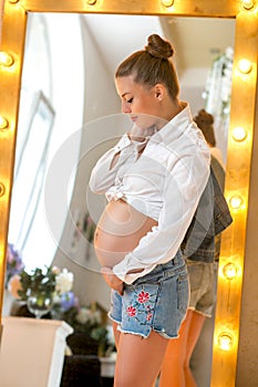 Pregnant happy woman touching her belly. Pregnant young mother portrait, caressing her belly and smiling. Healthy Pregnancy
