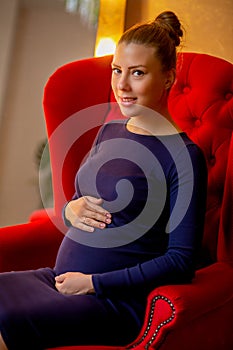 Pregnant happy woman touching her belly. Pregnant young mother portrait, caressing her belly and smiling. Healthy Pregnancy