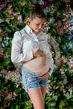 Pregnant happy woman touching her belly. Pregnant young mother portrait, caressing her belly and smiling. Healthy Pregnancy