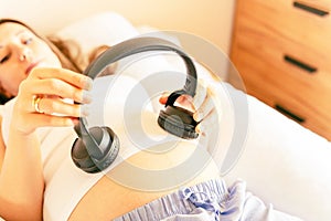 Pregnant headphones music. Pregnancy woman listening to music. Mother belly listen headphones sound. Concept maternity