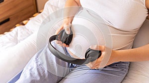 Pregnant headphones music. Pregnancy woman listening to music. Mother belly listen headphones sound. Concept maternity