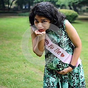 A pregnant Indian lady poses for outdoor pregnancy shoot and hands on belly, Indian pregnant woman puts her hand on her stomach