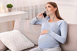 Pregnant Lady Calling Doctor Feeling Bad Sitting On Sofa Indoor