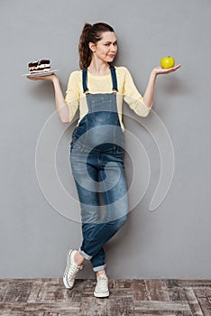 Pregnant lady choosing between sweet cake and apple.