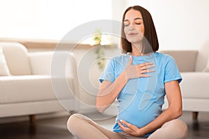 Pregnant lady engaging in yoga breathing exercises in home interior