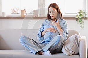 Pregnant lady feeling bad touching tummy and chest at home