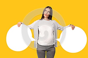 Pregnant Lady Holding Two Speech Bubbles Near Belly, Yellow Background