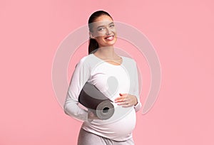 Pregnant Lady Holding Yoga Mat Smiling Standing On Pink Background