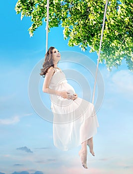 Pregnant lady sitting on the wooden swing