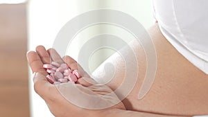 Pregnant latin american woman pouring pink medicine pills into her hand