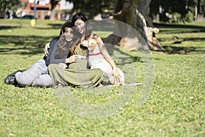 Pregnant latin woman sitting next to her daughter and dog posing looking at the camera