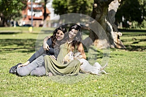 Pregnant latin woman sitting next to her daughter and dog posing looking at the camera