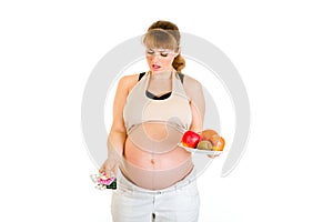 Pregnant making choice between pills and fruits