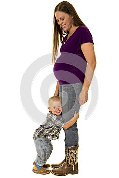 Pregnant mom in boots young boy hug her legs