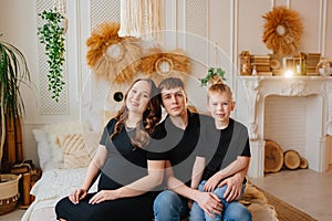 pregnant mom, dad and son in black robes on a bed in a white room. happy family.