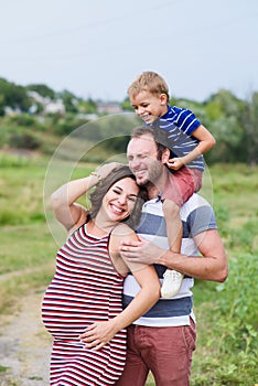 Pregnant mom and dad with son on his shoulders