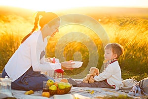 Pregnant mom and her beautiful little son at a picnic. Happy family and healthy eating concept