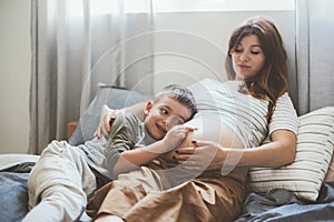 Pregnant mom playing with child in bedroom