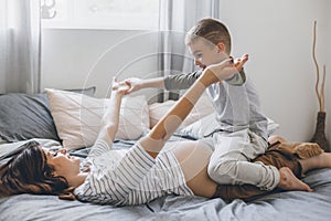 Pregnant mom playing with child in bedroom