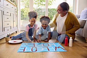 Pregnant Mother With Children Making Welcome Home Banner For Army Father