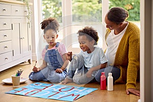 Pregnant Mother With Children Making Welcome Home Banner For Army Father