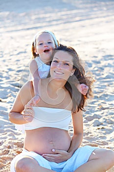 Pregnant mother and daughter on the beach