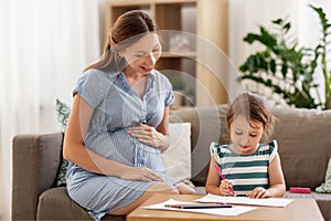 Pregnant mother and daughter drawing at home