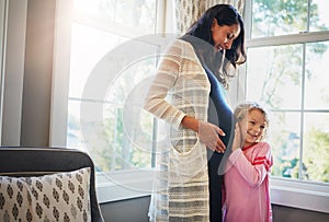Pregnant, mother and daughter with listening to tummy for baby kick, excited for newborn and curious with smile in home