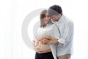 Pregnant Mother and father standing hugging holding belly, family concept.