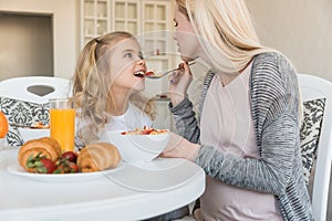 pregnant mother feeding daughter