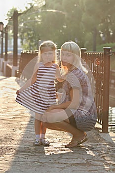 Pregnant mother and her cute daughter pose in sunny summe