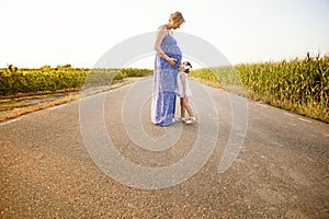 Pregnant mother and her daughter between cornfields