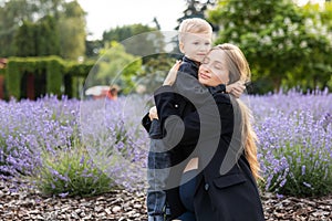 Pregnant mother and her little son spending time together in the park, hugging and smiling