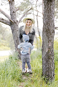 Pregnant mother and her little son walking in the forest and spending time together