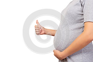 Pregnant mother holding belly and give thumb up with isolated on white background copy space. Pregnancy woman and her baby or