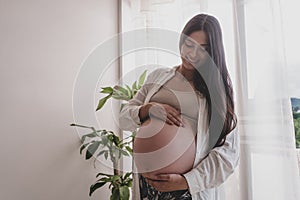 Pregnant mother holding her belly with her hands and feeling the baby& x27;s kicks