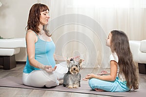 Pregnant mother meditating at home with her daughter and pet dog