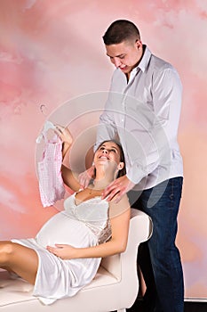 Pregnant mother showing baby clothes