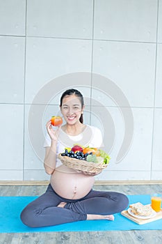 The pregnant mother is showing food and fruit to nourish the pregnancy