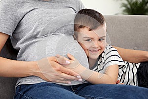 Pregnant mother and son sitting together on sofa at home