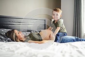 A Pregnant mother and son spending time together in bedroom