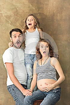 Pregnant mother with teen daughter and husband. Family studio portrait over brown background