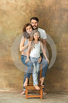 Pregnant mother with teen daughter and husband. Family studio portrait over brown background