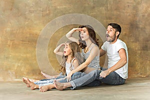 Pregnant mother with teen daughter and husband. Family studio portrait over brown background