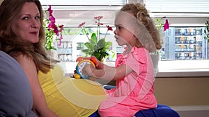 Pregnant mother woman and lovely daughter girl playing with toy clock on stomach