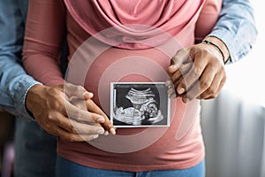 Pregnant Muslim Woman And Her Husband Holding Baby Sonogram Picture