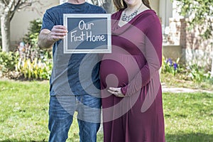 Pregnant new family buying their new home with sign